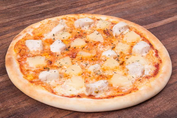 Sıcak pizza dilimi, erimiş peynirle ahşap bir masada.