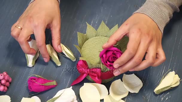 Close-up of corrugated paper hack bright pink in female hands. Female decorator folds of paper origami flower button. Modern art: making crafts out of paper to decorate parties, weddings and march 8 — Stock Video