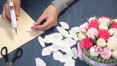 Oluklu kağıt kesmek parlak pembe kadın elinde close-up. Kağıt origami çiçek düğmesinin kadın dekoratör pas geçiyor. Modern Sanat: partiler, Düğünler ve 8 Mart süslemek için kağıt el sanatları yapma