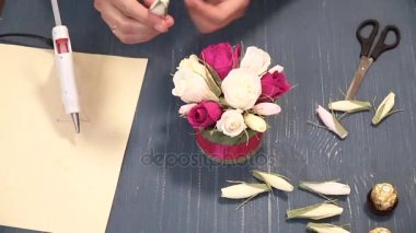 Oluklu kağıt kesmek parlak pembe kadın elinde close-up. Kağıt origami çiçek düğmesinin kadın dekoratör pas geçiyor. Modern Sanat: partiler, Düğünler ve 8 Mart süslemek için kağıt el sanatları yapma
