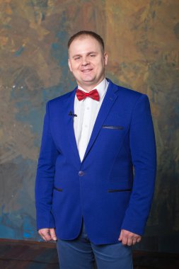 Mavi elbiseli mutlu zarif adam duvar arka plan ayakta duruyor