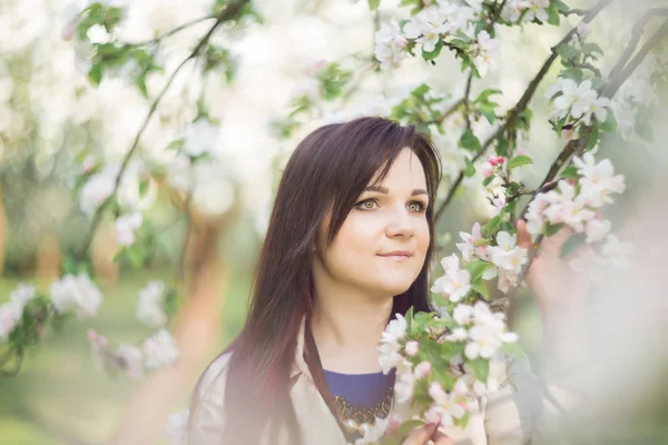 Krásná mladá brunetka žena stojící vedle jabloni na teplý jarní den — Stock fotografie