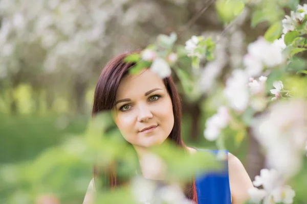 Krásná mladá brunetka žena stojící vedle jabloni na teplý jarní den — Stock fotografie