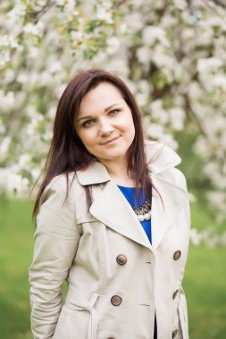 bir sıcak bahar gününde çiçek açması elma ağacının yanında duran güzel genç esmer kadın