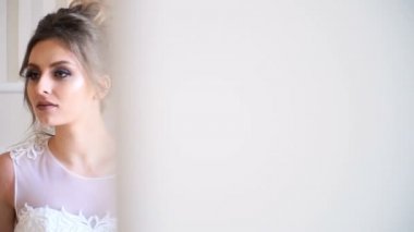 Güzel genç gelin portresi. Bir kız bir otel odasında poz. Bir bayan bir buket gül cam kenarında oturuyor. Otelin bekliyor gelin