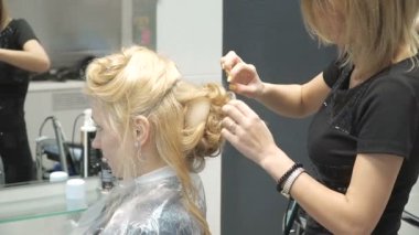 Güzellik Salonu genç bir kadın portresi: muhteşem bir ayar bukleler oluşturma. Kuaför bir sarışın güzel bir saç modeli yapar. Saç Bakımı ve görüntüsü oluşturma.