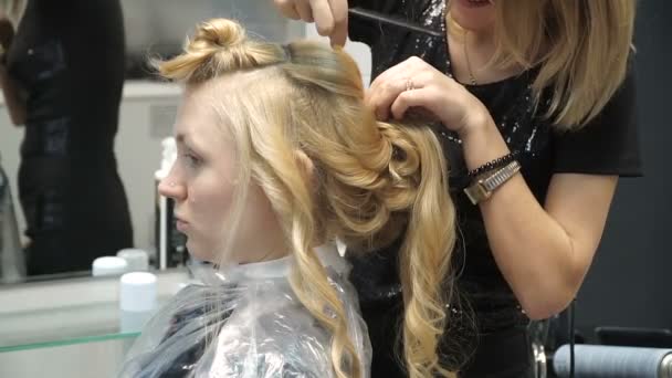 Retrato de uma jovem mulher em um salão de beleza: criando um cenário magnífico de cachos. Uma loira em um cabeleireiro faz um belo penteado. Cuidados com o cabelo e criar uma imagem . — Vídeo de Stock