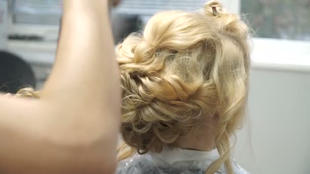 Portrait of a young woman in a beauty salon: creating a magnificent setting from curls. A blonde in a hairdresser does a beautiful hairstyle. Hair care and creating an image. — Stock Video