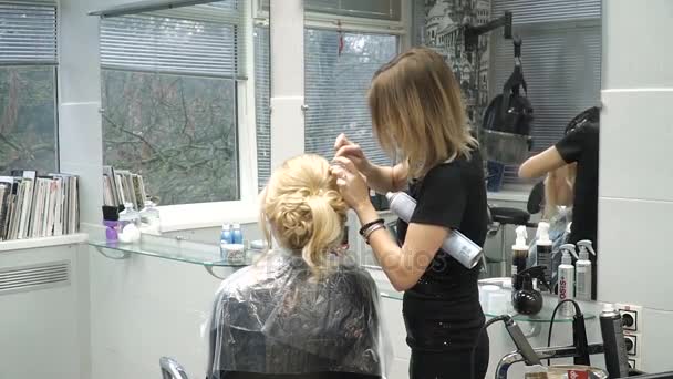 Portrait of a young woman in a beauty salon: creating a magnificent setting from curls. A blonde in a hairdresser does a beautiful hairstyle. Hair care and creating an image. — Stock Video