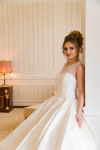 Portret van mooie jonge bruid. Een meisje is poseren in een hotelkamer. Een dame Is de moeite waard met bij het raam. bruid wachten in hotel. — Stockfoto