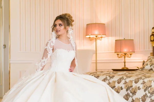 Portrait of beautiful young bride. A girl is posing in a hotel room. A lady Is worth with by the window. bride waiting in hotel.