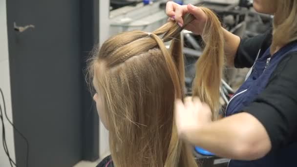 Portrait d'une jeune femme dans un salon de beauté : créer un cadre magnifique à partir de boucles. Une blonde dans un coiffeur fait une belle coiffure. Soins capillaires et création d'une image . — Video