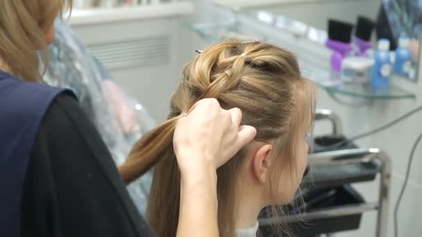 一个年轻女子在一家美容院的肖像︰ 从卷发创建一个壮观的设置。一位金发女郎在一名理发师做漂亮的发型啊。头发护理和创建映像. — 图库视频影像