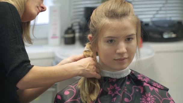 Porträtt av en ung kvinna i en skönhetssalong: att skapa en magnifik miljö från lockar. En blondin i en frisör gör en vacker frisyr. Hårvård och skapa en bild. — Stockvideo