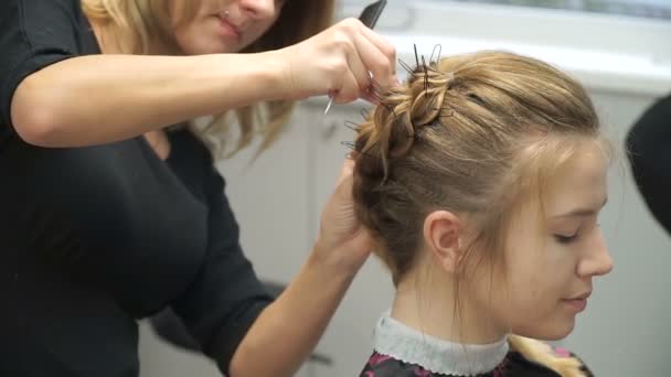 一个年轻女子在一家美容院的肖像︰ 从卷发创建一个壮观的设置。一位金发女郎在一名理发师做漂亮的发型啊。头发护理和创建映像. — 图库视频影像