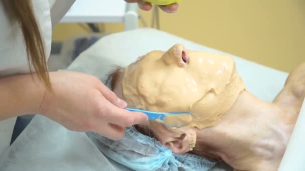 En äldre kvinna ges en mask efter Rf förfarande lyft i en kosmetologi klinik. — Stockvideo
