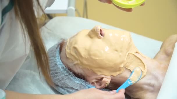 Una donna anziana viene data una maschera dopo la procedura di sollevamento RF in una clinica di cosmetologia . — Video Stock