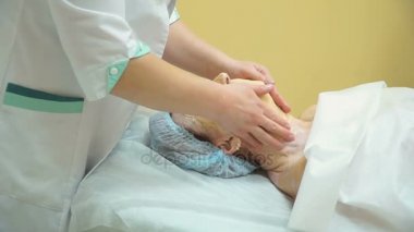 Yaşlı bir kadın kozmetik kliniğinde kaldırma Rf yordam sonra profesyonel yüz masaj verilir.