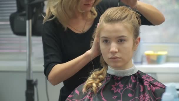 Porträtt av en ung kvinna i en skönhetssalong: att skapa en magnifik miljö från lockar. En blondin i en frisör gör en vacker frisyr. Hårvård och skapa en bild. — Stockvideo