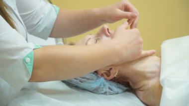 Yaşlı bir kadın kozmetik kliniğinde kaldırma Rf yordam sonra profesyonel yüz masaj verilir.