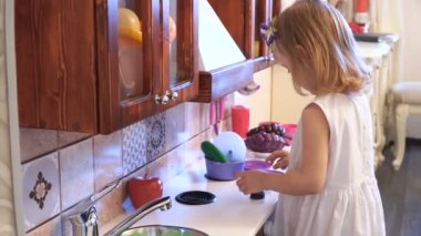 Aktif küçük okul öncesi yaş çocuk, şirin bebek kız sarışın kıvırcık saçlı, ahşap mutfak, oynarken gösterir çalış mutfakta