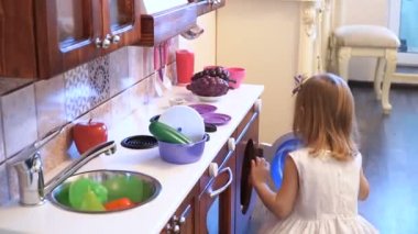 Aktif küçük okul öncesi yaş çocuk, şirin bebek kız sarışın kıvırcık saçlı, ahşap mutfak, oynarken gösterir çalış mutfakta