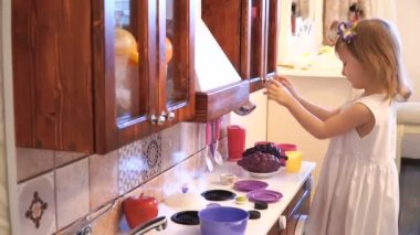 Aktif küçük okul öncesi yaş çocuk, şirin bebek kız sarışın kıvırcık saçlı, ahşap mutfak, oynarken gösterir çalış mutfakta