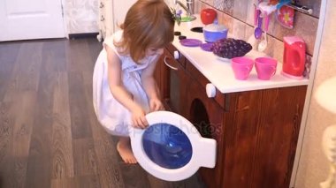 Aktif küçük okul öncesi yaş çocuk, şirin bebek kız sarışın kıvırcık saçlı, ahşap mutfak, oynarken gösterir çalış mutfakta