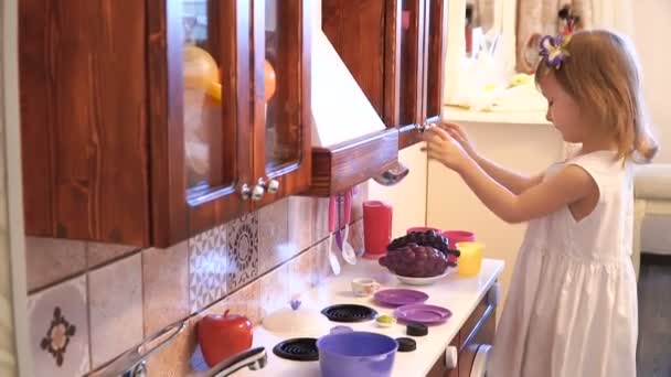Aktív kis óvodai kor gyermeke, aranyos kisgyermek lány szőke göndör haja, azt mutatja játszott konyha, fából készült, játszik a konyhában — Stock videók