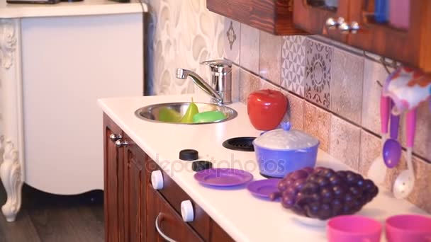 Aktives kleines Kind im Vorschulalter, niedliches Kleinkind mit blonden Locken, zeigt Spielküche, aus Holz, spielt in der Küche — Stockvideo