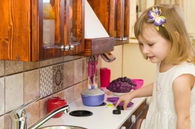 Aktif küçük okul öncesi yaş çocuk, şirin bebek kız sarışın kıvırcık saçlı, ahşap mutfak, oynarken gösterir çalış mutfakta