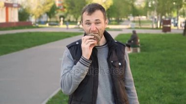 Tatlı yiyecek ve insan kavramı. genç adam parkta çikolatalı kek yeme