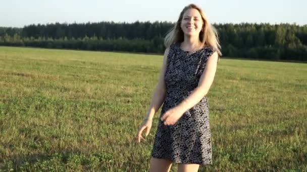 Schoonheid romantische jonge vrouw buitenshuis. Mooi model meisje in jurk op het veld in zonlicht. Vrolijke jonge vrouw die ter plaatse in het veld dwarrelen bij zonsondergang. — Stockvideo