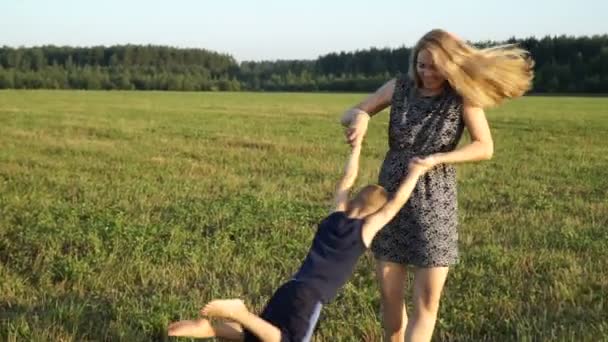 Moeder speelt met zoon bij veld bij zonsondergang. Slow mo — Stockvideo