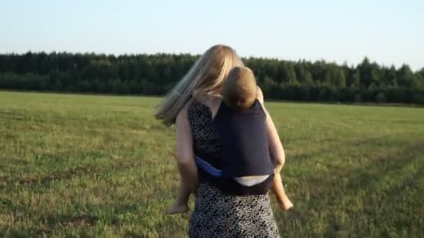 Moeder speelt met zoon bij veld bij zonsondergang. Slow mo — Stockvideo