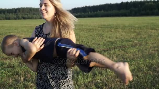 Madre juega con su hijo en el campo al atardecer. Lento mo — Vídeos de Stock