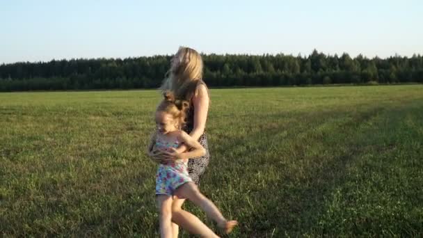 Madre gioca con la figlia sul campo al tramonto. Lento mo — Video Stock