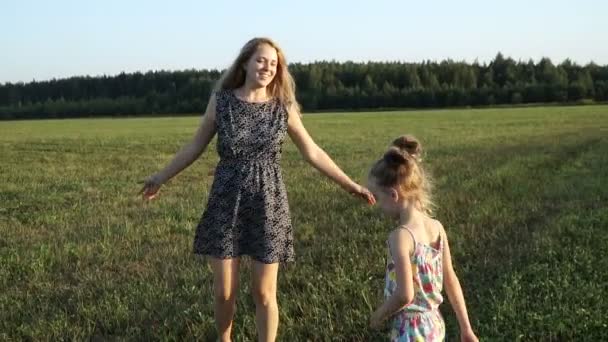 Madre gioca con la figlia sul campo al tramonto. Lento mo — Video Stock