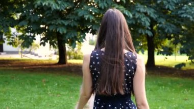 Parkta yürüyüş ve etrafında dönen bir gülümseme ile güzel mutlu genç kız. Mutlu görünüyor. Yavaş çekim. Esmer kız ile yürüyüş