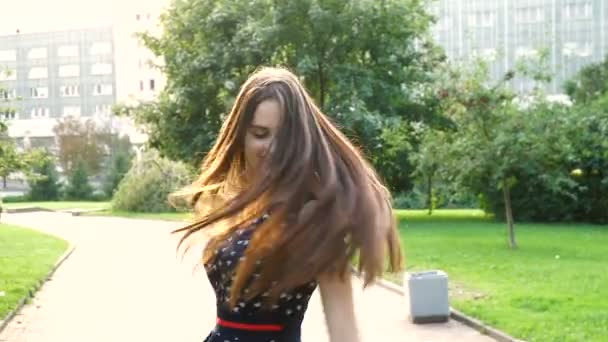 Młoda, piękna, atrakcyjna kobieta w sukni stylowe, pozowanie na kamery. Ona się śmieje, pozuje do kamery, jej włosy wiejący wiatr, patrząc bardzo szczęśliwy. zwolnionym tempie — Wideo stockowe