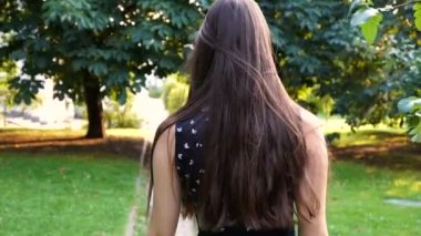 Şirin esmer parkta yürüyor. ağır çekim