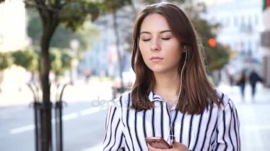 Telefondan kulaklıklar müzik dinlemek sokakta tutan güzel kadın danslar. Ağır çekim