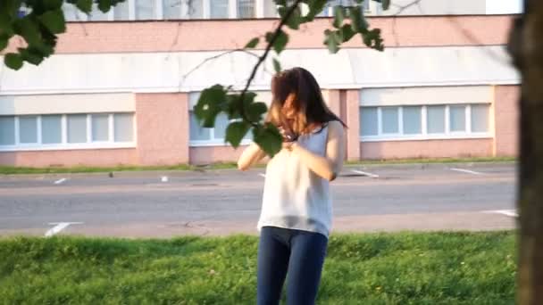 Giovane bella ragazza che balla in un parco. donna in jeans che balla per strada — Video Stock