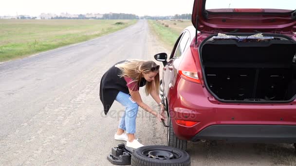 Mujer vestida sexualmente rodando rueda de repuesto en la carretera — Vídeo de stock