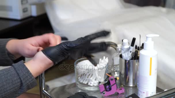 Specialist of permanent make-up wears rubber gloves of black color. — Stock Video