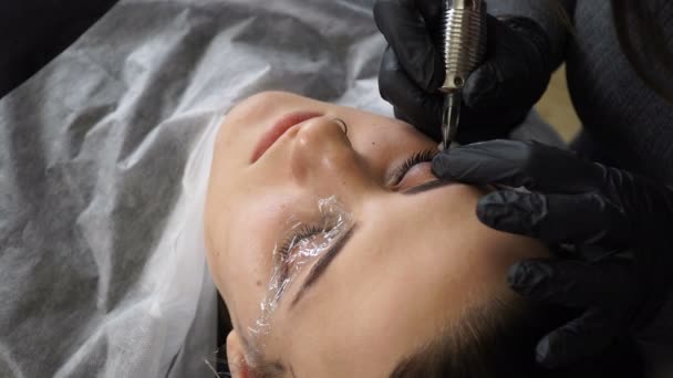 Esteticista, especialista en maquillaje permanente haciendo delineador de ojos maquillaje permanente — Vídeos de Stock