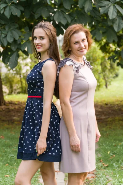 Nahaufnahme Porträt der erwachsenen Tochter und Mutter im Freien. hübsche Brünette und ihre Mutter schauen im Sommer im Park in die Kamera. — Stockfoto