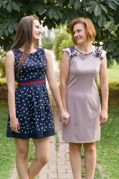 Nahaufnahme Porträt der erwachsenen Tochter und Mutter im Freien. hübsche Brünette und ihre Mutter schauen im Sommer im Park in die Kamera. — Stockfoto