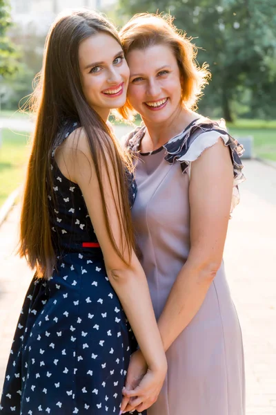 Nahaufnahme Porträt der erwachsenen Tochter und Mutter im Freien. hübsche Brünette und ihre Mutter schauen im Sommer im Park in die Kamera. — Stockfoto