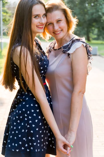 Nahaufnahme Porträt der erwachsenen Tochter und Mutter im Freien. hübsche Brünette und ihre Mutter schauen im Sommer im Park in die Kamera. — Stockfoto